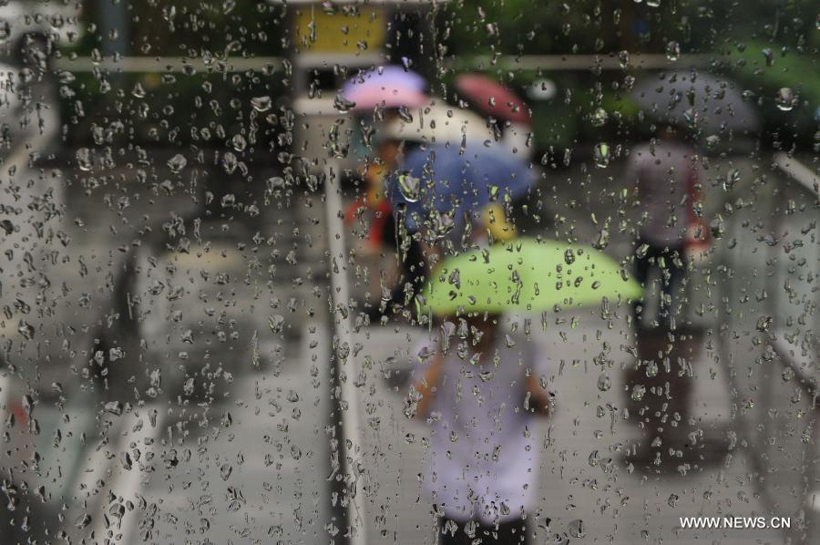 Pedestrians walk amid rain in Shenzhen, south China's Guangdong Province, May 26, 2013. Torrential rain hit most parts of Guangdong Province from Saturday to Sunday. (Xinhua/Mao Siqian)