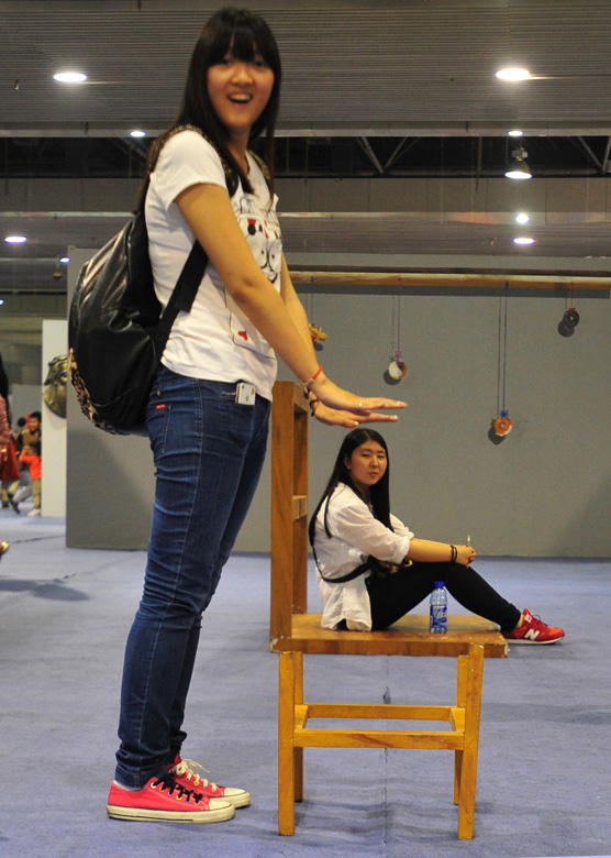 Two visitors experience the visual illusion of a 4D creation in Wuhan, Hubei province on May 18, 2013. (Xinhua Photo/ Xiao Yijiu)