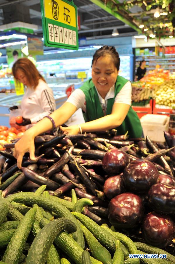 A staff member arranges vegetables at a supermarket in Xingtai, north China's Hebei Province, May 27, 2013. Prices of edible farm produce in 36 major Chinese cities declined for five consecutive weeks, the Ministry of Commerce said on May 27. The average wholesale prices for 18 vegetables on the monitored list dropped by 5.2 percent week on week and declined by 21.9 percent over the price of five weeks ago. (Xinhua/Zhu Xudong)