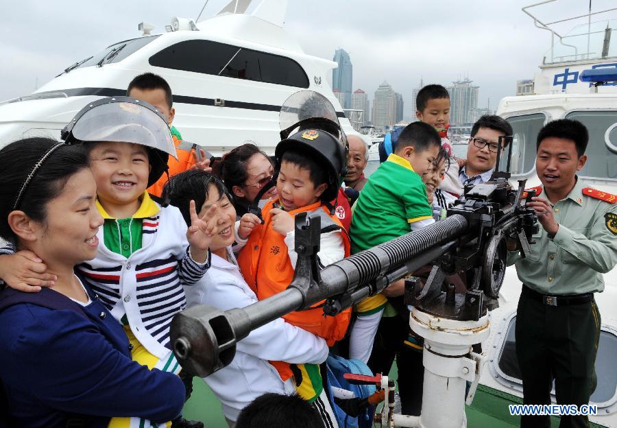 Children visit a patrol boat during an open day of local frontier defense vessel division in Qingdao, a coastal city in east China's Shandong Province, May 28, 2013. (Xinhua/Li Ziheng)