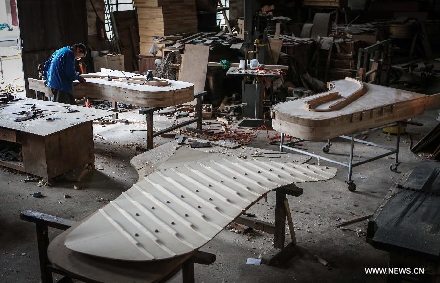 Photo taken on May 8, 2013 shows Zhang Gangning, a piano maker, makes piano at a warehouse he rents in Nanjing, capital of east China's Jiangsu Province. Zhang's interest in piano-making started 13 years ago. (Xinhua/Yang Lei)