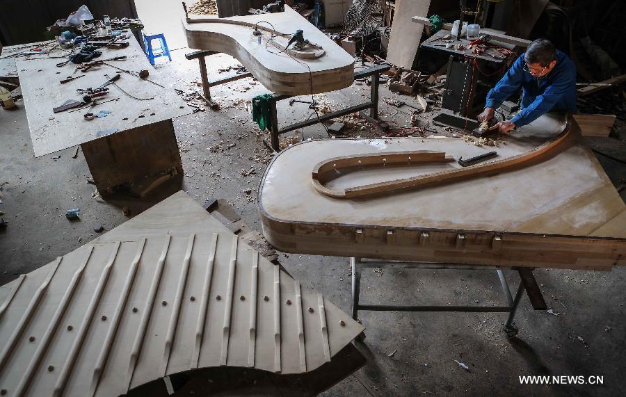 Photo taken on May 8, 2013 shows Zhang Gangning, a piano maker, makes piano at a warehouse he rents in Nanjing, capital of east China's Jiangsu Province. (Xinhua/Yang Lei)