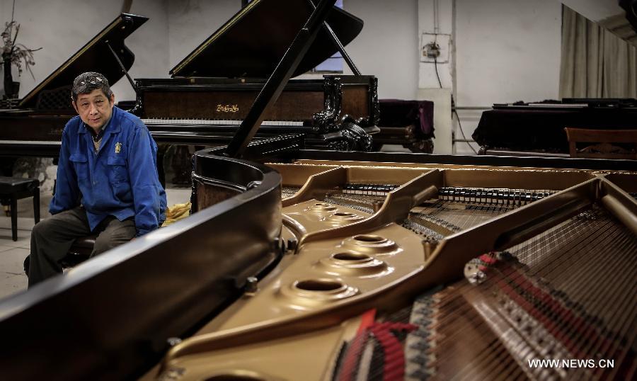 Photo taken on May 8, 2013 shows Zhang Gangning, a piano maker, looks at a piano he made in Nanjing, capital of east China's Jiangsu Province.  (Xinhua/Yang Lei)