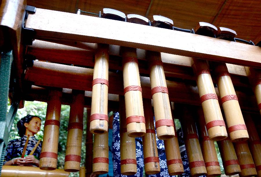 A bandswoman plays musical instruments made with bamboo at the Lanxi Valley Rain Forest Scenic Area in Chongyi County, east China's Jiangxi Province, May 28, 2013. Chongyi boasts of abundant resources of moso bamboo. (Xinhua/Wang Song) 