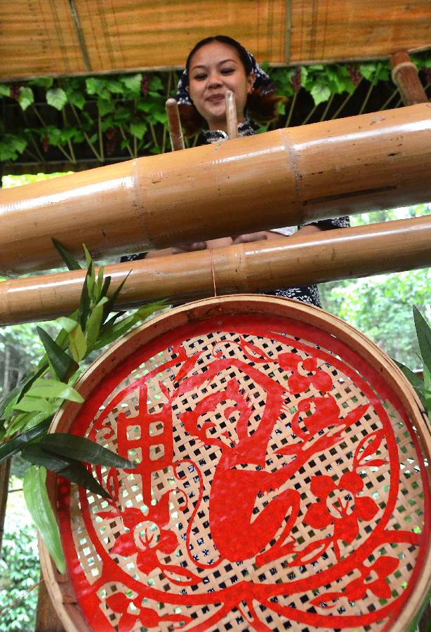 A bandswoman plays musical instruments made with bamboo at the Lanxi Valley Rain Forest Scenic Area in Chongyi County, east China's Jiangxi Province, May 28, 2013. Chongyi boasts of abundant resources of moso bamboo. (Xinhua/Wang Song) 