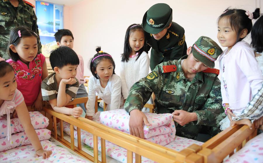 Soldiers teach students to fold quilts in Dalian, northeast China's Liaoning Province, May 30, 2013. Various activities are held across China to celebrate the coming International Children's Day. (Xinhua/Jiang Bing)