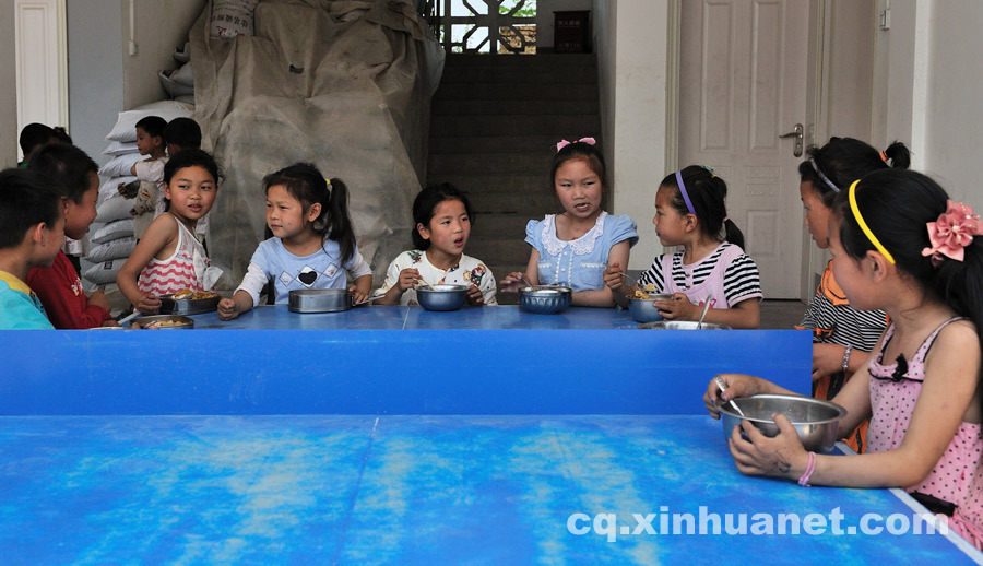 The students have meals on a table-tennis table since there is no cafeteria at school. (Photo by Huang Junhui/ cq.xinhuanet.com)