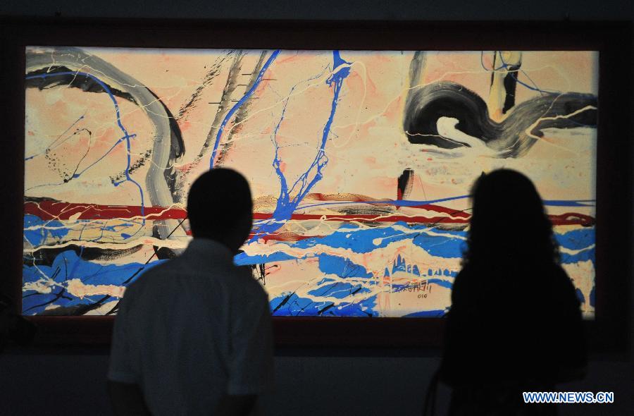 People look at a painting of Antonio Meneghetti, the father of onto-psychology, at an exhibition in Wuhan, capital of central China's Hubei Province, May 30, 2013. An exhibition of Meneghetti's paintings kicked off at the provincial museum here on Thursday. Meneghetti, who was supposed to attend his exhibition's opening ceremony, has passed away on May 20 at the age of 77 in Italy. (Xinhua/Xiao Yijiu)