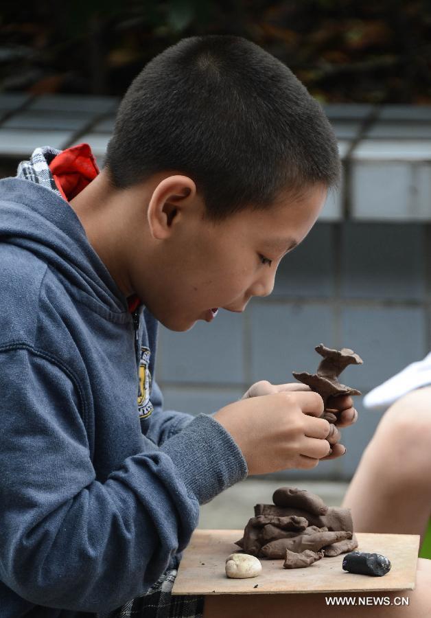 A student of Zhicun Central Elementary School makes a clay sculpture during the school's Mud Culture Festival in Chongfu Township of Tongxiang City, east China's Zhejiang Province, May 31, 2013. (Xinhua/Xu Yu)