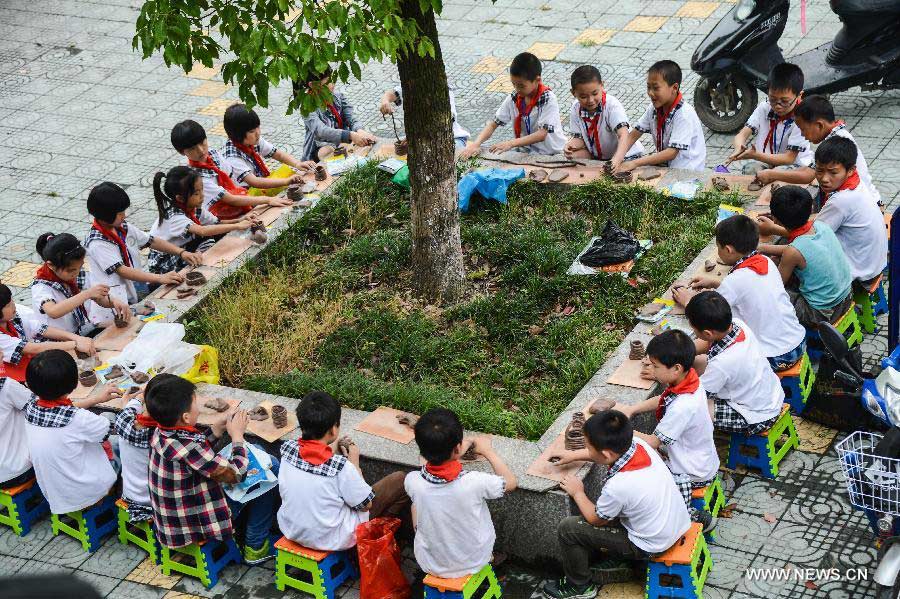 Students of Zhicun Central Elementary School make clay sculptures during the school's Mud Culture Festival in Chongfu Township of Tongxiang City, east China's Zhejiang Province, May 31, 2013. (Xinhua/Xu Yu)