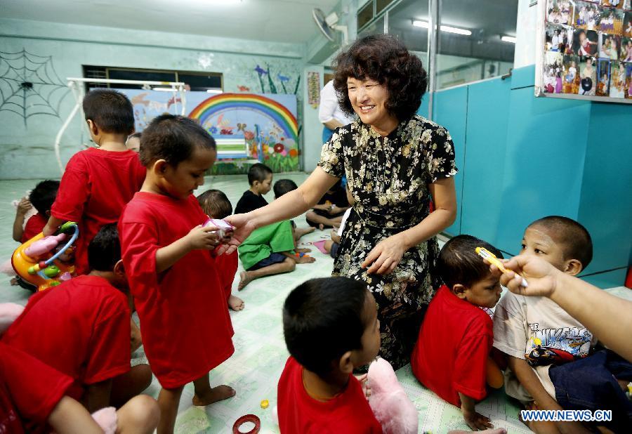 Wife of Ambassador Madame Ruan Wei (3rd R) presents gifts to the children at a residential nursery in Yangon, Myanmar, June 1, 2013. A women team of the Chinese Embassy in Myanmar, led by wife of Ambassador Madame Ruan Wei, visited a residential nursery in Shwegondaing, Yangon Saturday, the International Children's Day, for a festive call on children accommodated in the nursery. (Xinhu/U Aung)