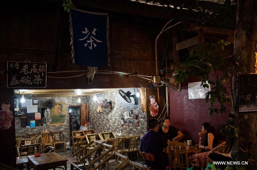 Tourists have tea in a teahouse on the Kuan Zhai Xiang Zi, or the Wide and Narrow Alleys in Chengdu, capital of southwest China's Sichuan Province, May 31, 2013. Consisting of three remodeled historical community alleyways dating back to the Qing Dynasty, the Wide and Narrow Alleys are now bordered with exquisitely decorated tea houses, cafes, boutiques and bookshops. The 2013 Fortune Global Forum will be held in Chengdu from June 6 to June 8. Chengdu, a city known for its slow living pace, is developing into an international metropolis with its huge economic development potential as well as its special cultural environment. (Xinhua/Li Hualiang)