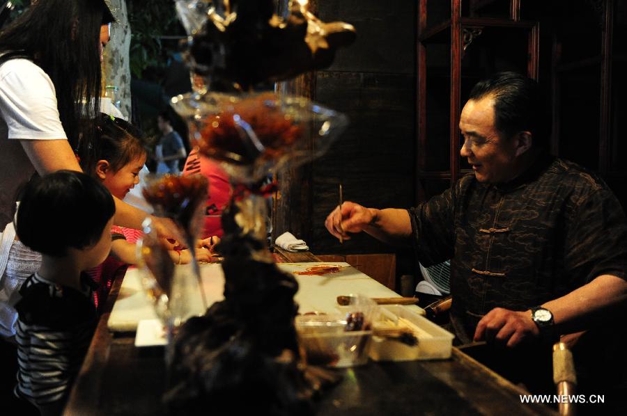 Children wait for Daotangren, a sugar-made sculpture with long history, on the Kuan Zhai Xiang Zi, or the Wide and Narrow Alleys in Chengdu, capital of southwest China's Sichuan Province, May 31, 2013. Consisting of three remodeled historical community alleyways dating back to the Qing Dynasty, the Wide and Narrow Alleys are now bordered with exquisitely decorated tea houses, cafes, boutiques and bookshops. The 2013 Fortune Global Forum will be held in Chengdu from June 6 to June 8. Chengdu, a city known for its slow living pace, is developing into an international metropolis with its huge economic development potential as well as its special cultural environment. (Xinhua/Li Hualiang)