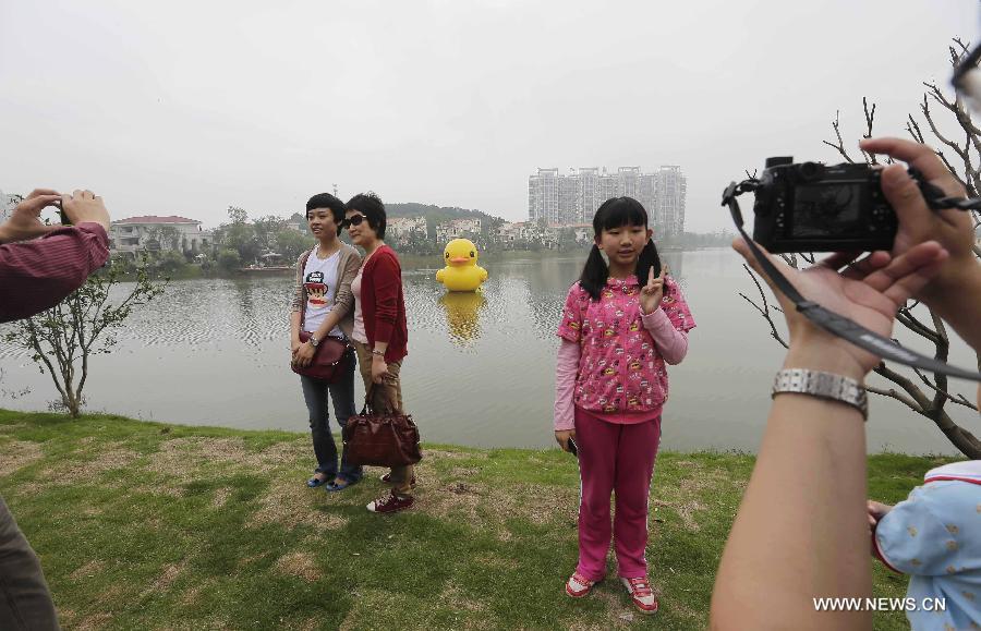 People take photos near a mini rubber duck floating on a lake in the Hannan District of Wuhan, capital of central China's Hubei Province, June 1, 2013. The duck, made by a property company, is a mini copy of the huge rubber duck which appeared in Hong Kong, south China, on May 2. (Xinhua) 