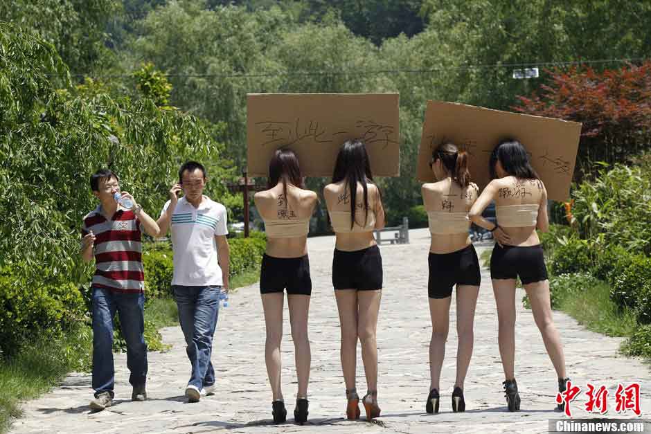 Four women hold boards with words demanding for a special place where the tourists can sign their signitures at will in Yangzigou scenic spot, in centeral China's Henan Province, June 2, 2013. (Source: chinanews.com)