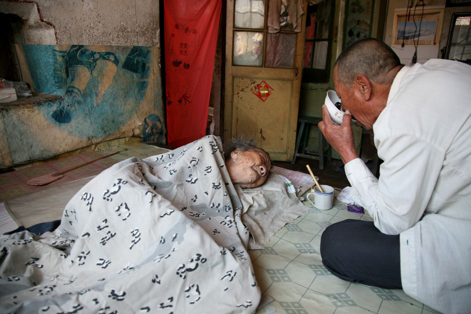 After feeding his mother, Wang eats the leftovers on May 29, 2013. (Xinhua/Ren Lihua)