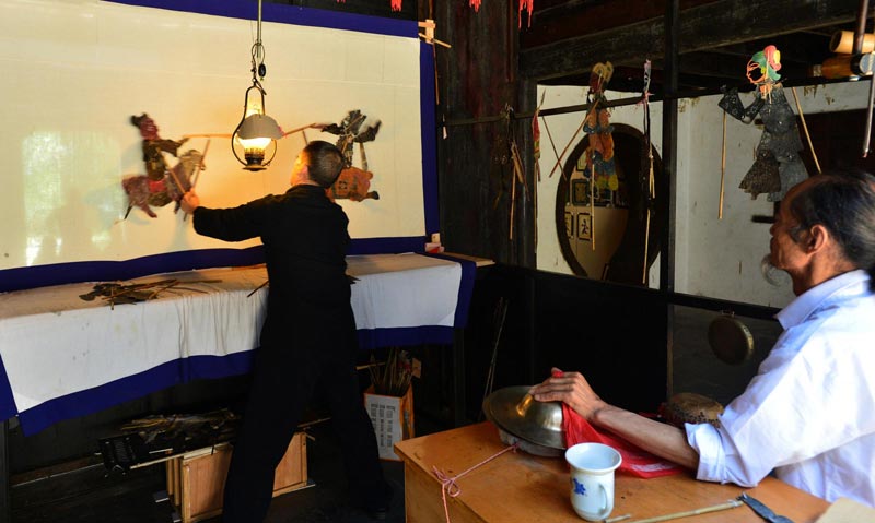 Two experts of the intangible heritage shadow play art perform for audiences at the Mount Phoenix scenic area in Zigui county, Hubei province, June 2, 2013. (Xinhua)