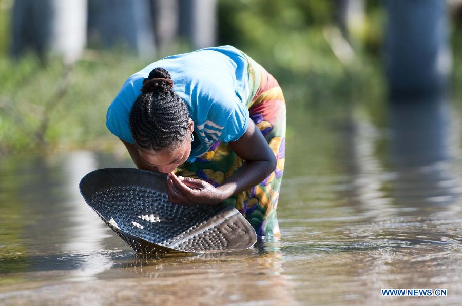 A woman looks for sapphire in a river in Ilakaka town, the famous sapphire town in southwest Madagascar, on May 31, 2013. Since the discovery of alluvial sapphire deposits in 1998, the population had boomed from 40 residents to near 60,000 by 2005, including many businessmen from Thailand, India, France, China, etc., most of whom dreamed to become rich in one night to find sapphires. Madagsacar, famous for its sapphire production, stood alongside Australia as one of the world's two largest sapphire producers at its peak period. There are still sapphire mines operating around Ilakaka, but most deposits are located deeper below the surface now, and miners have to work much harder to extract sapphires. Due to the deep location and political crisis, Madagascar has not managed to regain its former glory as a primary producer of sapphires. (Xinhua/He Xianfeng)