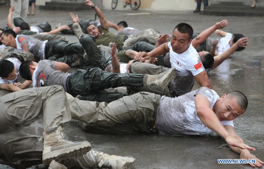 Trainees roll over the ground during a VIP security training course at the Genghis Security Academy in Beijing, capital of China, June 6, 2013. Some 70 trainees, including six females and three foreigners, will receive intensified training at the bodyguard camp for over 20 hours per day in a week. One third of them will be eliminated. (Xinhua/Liu Changlong)