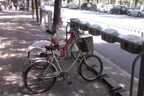 A public rental bike stands idle as other bicycles are parked at the rental area in Dongcheng district of Beijing, June 3, 2013. 