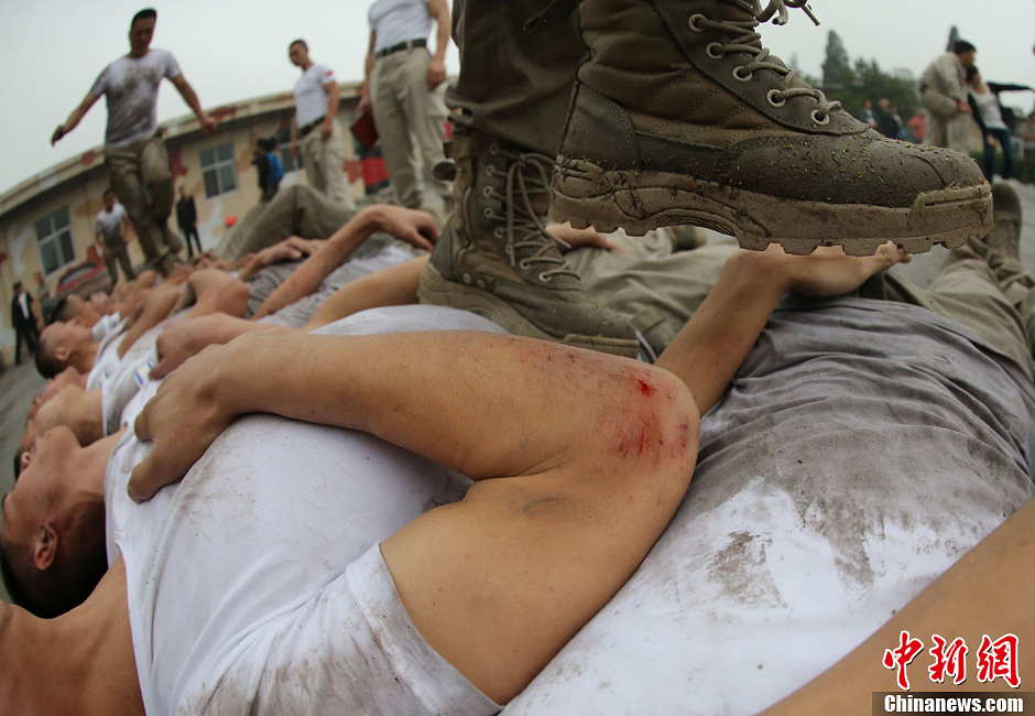 Trainees trample on fellow trainees during a VIP security training course at the Genghis Security Academy in Beijing, June 6, 2013. More than 70 trainees, including six women and three foreigners will receive high-intensity training for VIP security at a bodyguard camp in Beijing. They will train over 20 hours per day for one week. One third of the participants will be phased out at the end of the "Hell Week". (Photo/ Chinanews.com)