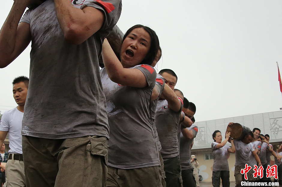 Trainees lift a log during a VIP security training course at the Genghis Security Academy in Beijing, June 6, 2013. More than 70 trainees, including six women and three foreigners will receive high-intensity training for VIP security at a bodyguard camp in Beijing. They will train over 20 hours per day for one week. One third of the participants will be phased out at the end of the "Hell Week".  (Photo/ Chinanews.com)