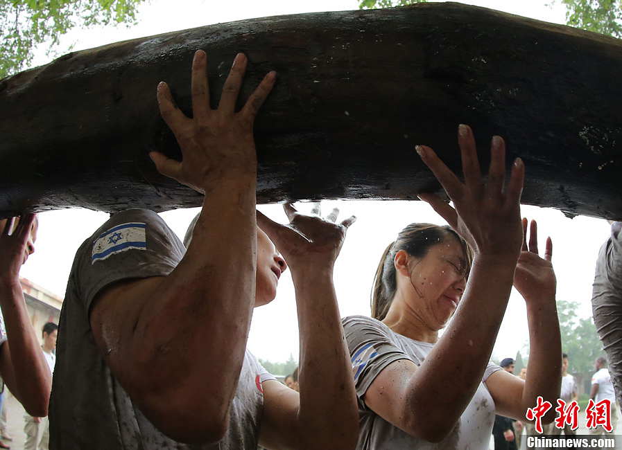 Trainees lift a log during a VIP security training course at the Genghis Security Academy in Beijing, June 6, 2013. More than 70 trainees, including six women and three foreigners will receive high-intensity training for VIP security at a bodyguard camp in Beijing. They will train over 20 hours per day for one week. One third of the participants will be phased out at the end of the "Hell Week".  (Photo/ Chinanews.com)