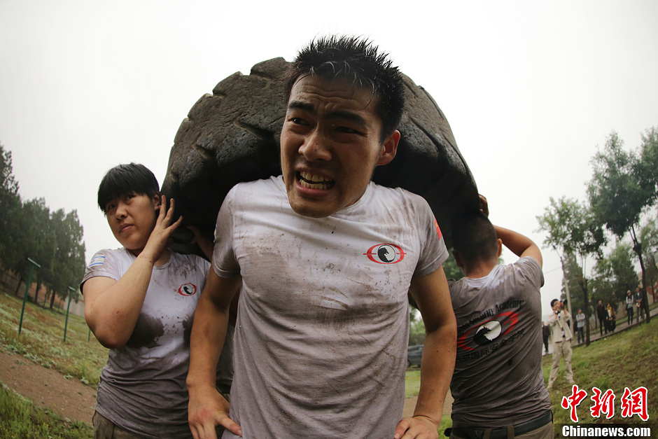 Trainees lift a tire during a VIP security training course at the Genghis Security Academy in Beijing, capital of China, June 6, 2013. More than 70 trainees, including six women and three foreigners will receive high-intensity training for VIP security at a bodyguard camp in Beijing. They will train over 20 hours per day for one week. One third of them will be eliminated. (Photo/ Chinanews.com)