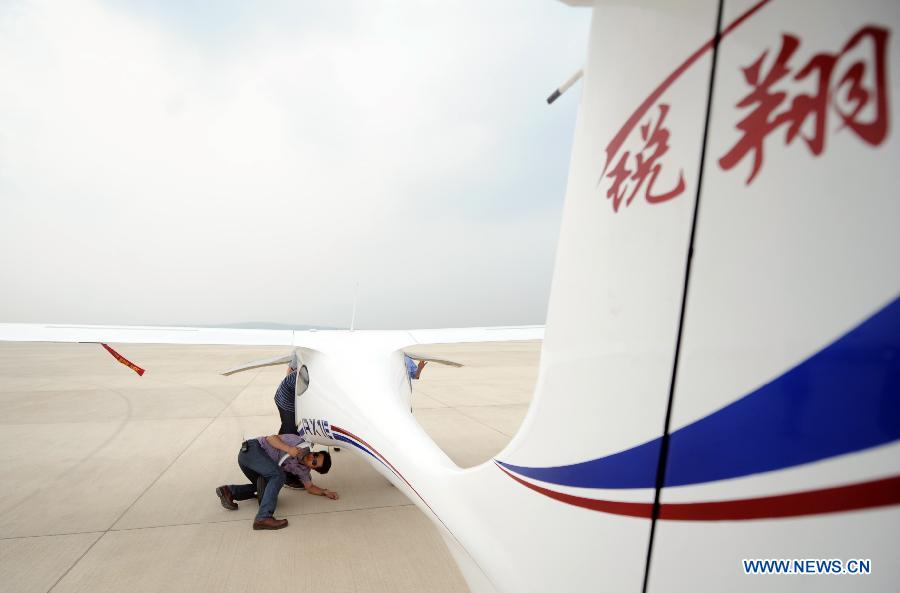 Technicians inspect an electric two-seater light sport airplane at the Caihu Airport in Shenyang, capital of northeast China's Liaoning Province, June 6, 2013. The lithium-battery-powered aircraft, independently-developed by Shenyang Aerospace University, had a successful test flight Friday. (Xinhua/Yang Qing)