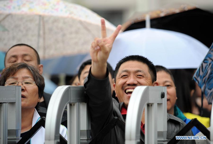 A man flashes a victory sign to his kid taking the national college entrance exam in Heihe, northeast China's Heilongjiang Province, June 7, 2013. Some 9.12 million applicants are expected to sit this year's college entrance exam.(Xinhua/Wang Jianwei) 