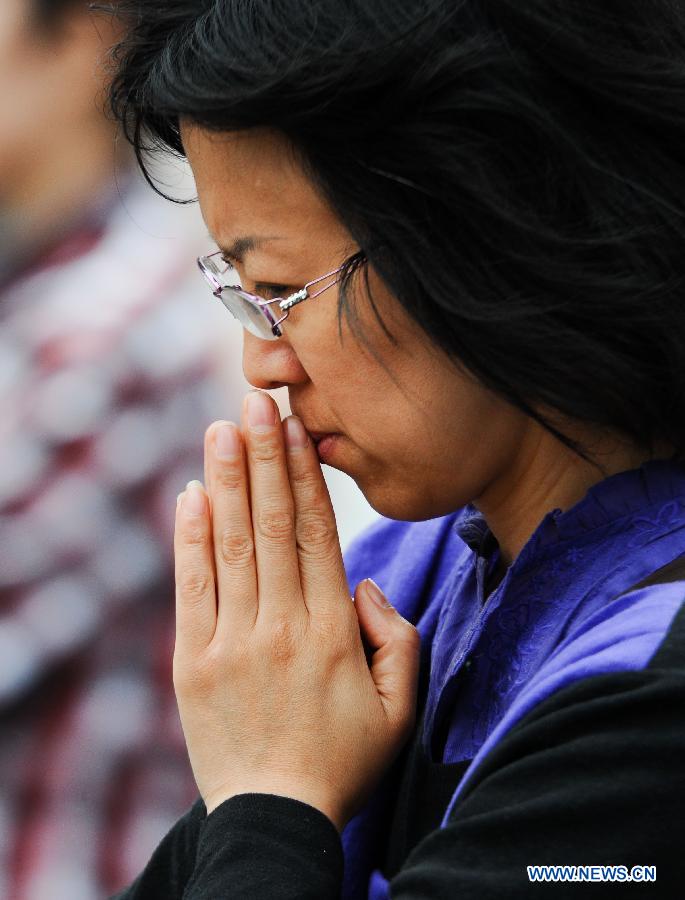 A mother prays for her child who is taking the national college entrance exam at the No. 11 High School in Changchun, capital of northeast China's Jilin Province, June 7, 2013. Some 9.12 million applicants are expected to sit this year's college entrance exam on June 7 and 8. (Xinhua/Xu Chang)