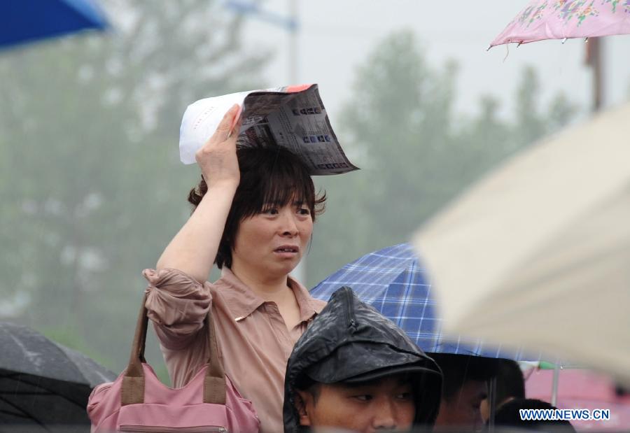 A mother waits in rain for her kid taking the national college entrance exam in Gu'an, north China's Hebei Province, June 7, 2013. Some 9.12 million applicants are expected to sit this year's college entrance exam. (Xinhua/Wang Xiao) 