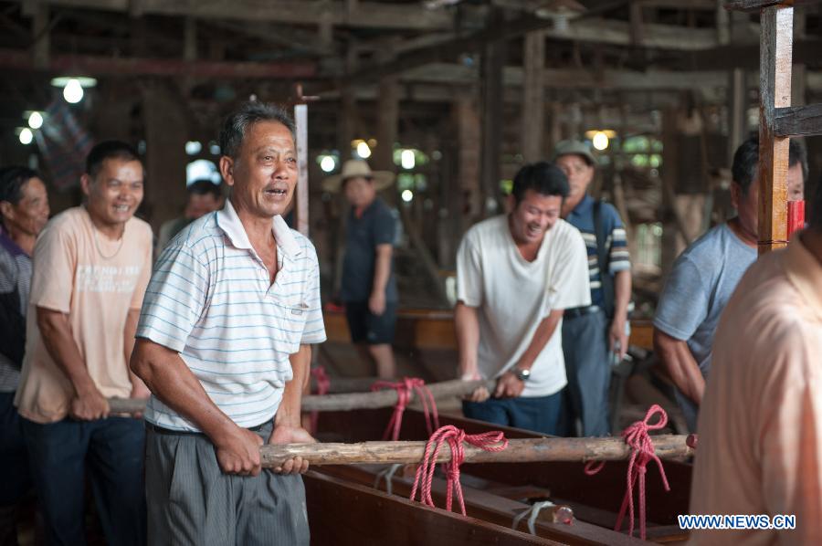 Villagers carry their new dragon boat during a launching ceremony at the Chenhanhui Shipyard at Shangjiao village in Guangzhou, capital of South China's Guangdong province, June 6, 2013. Chenhanhui Shipyard has been busy making new dragon boats and renovating old ones for the upcoming Dragon Boat Festival that falls on June 12 this year. People in many parts of China have the tradition to hold dragon boat races during the festival.(Photo/Xinhua)