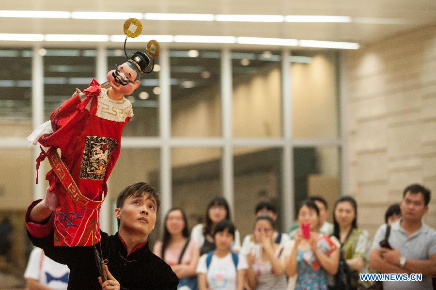 A performer operates a puppet during a Lingnan puppet show held by the Guangdong Provincial Puppet Art Theater at the Guangzhou Library to mark the 8th national Cultural Heritage Day in Guangzhou, capital of south China's Guangdong Province, June 8, 2013. (Xinhua/Mao Siqian)