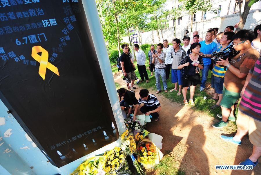 People lays flowers to mourn for the victims in front a pier of the elevated bus lane where a bus fire took place on Friday, in Xiamen, southeast China's Fujian Province, June 8, 2013. The bus fire has claimed 47 lives and hospitalized 34 passgengers. (Xinhua/Wei Peiquan)