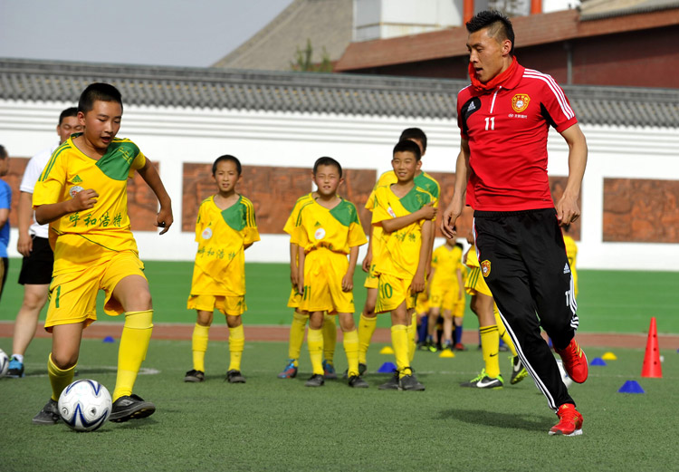 Who is the best: Yu Dabao plays football with students as Chinese footballers participate in the campus football activities. (Photo/Osports)