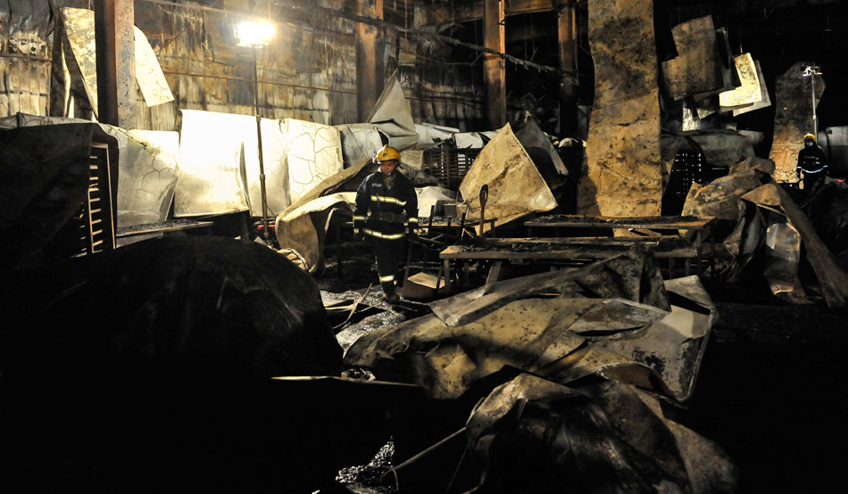 A rescuers works at the site of the accident after a fire occurred in a slaughterhouse of the Jilin Baoyuanfeng Poultry Company in Mishazi Township of Dehui city, northeast China's Jilin province, June 3, 2013. Death toll from the poultry processing plant fire had risen to 119. Over 300 workers were in the plant when the accident happened. (Xinhua/Wu Haofei)