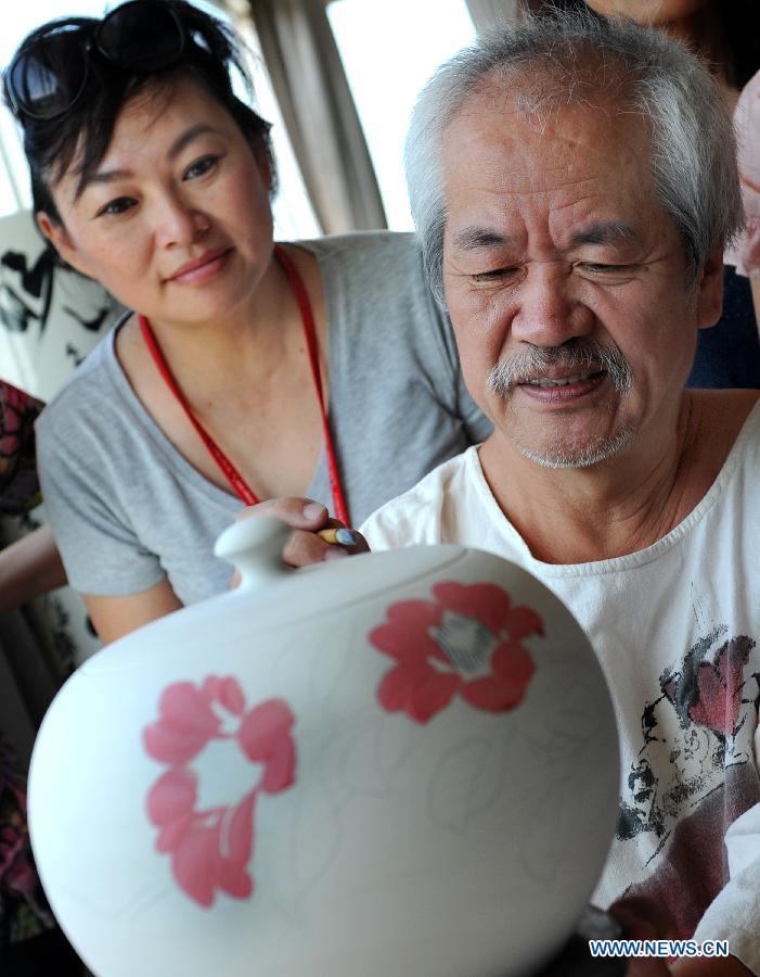 A visitor learns painting technique from Taiwan artist Chen Shi Hou (R) in the town of Yingge of Xinbei City in southeast China's Taiwan, June 8, 2013. Over 100 artists have set up workshops in Yingge, which is famous for ceramics production, providing opportunities for visitors to experience the process of making porcelains. (Xinhua/Tao Ming) 