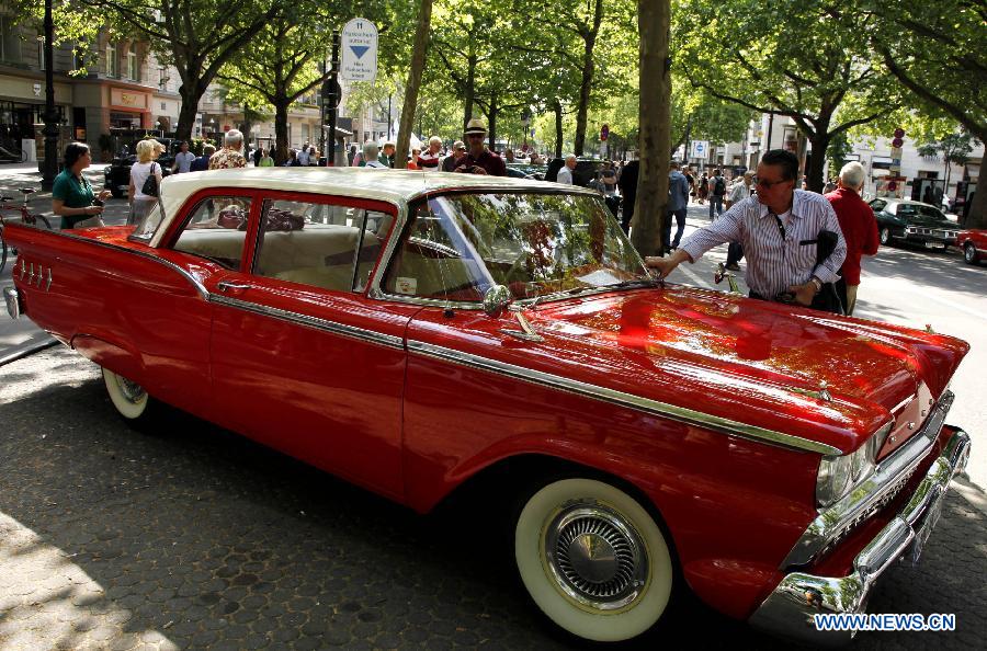 A visitor appreciates a classic old-timer car during a grand exhibition of the classic vintage cars, on the Kurfuerstendamm Avenue, in Berlin, Germany, June 8, 2013. Some 2,000 well-preserved and well-functioning classic vintage cars and limousines at least over 50-year-old are exhibited at the fair, with the motto "when luxury meets classics". (Xinhua/Pan Xu) 