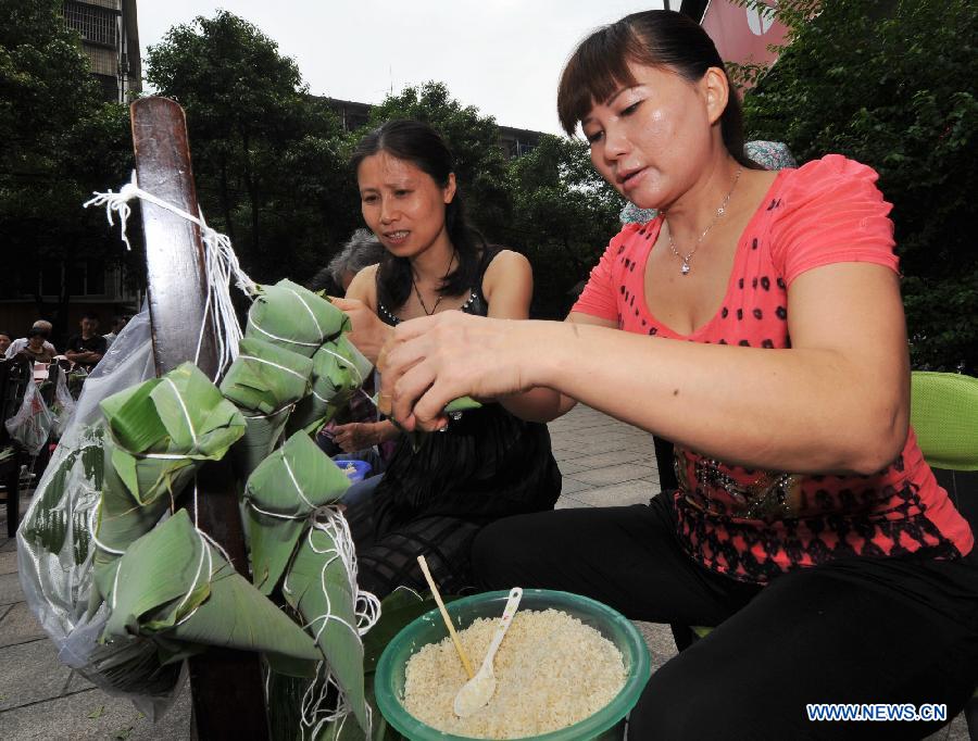 Contestants make Zongzi, a pyramid-shaped dumpling made of glutinous rice wrapped in bamboo or reed leaves, during a contest in celebration of the upcoming Dragon Boat Festival in Changsha, capital of central China's Hunan Province, June 9, 2013. The Dragon Boat Festival falls on the fifth day on the fifth month on the lunar calendar. (Xinhua/Long Hongtao)