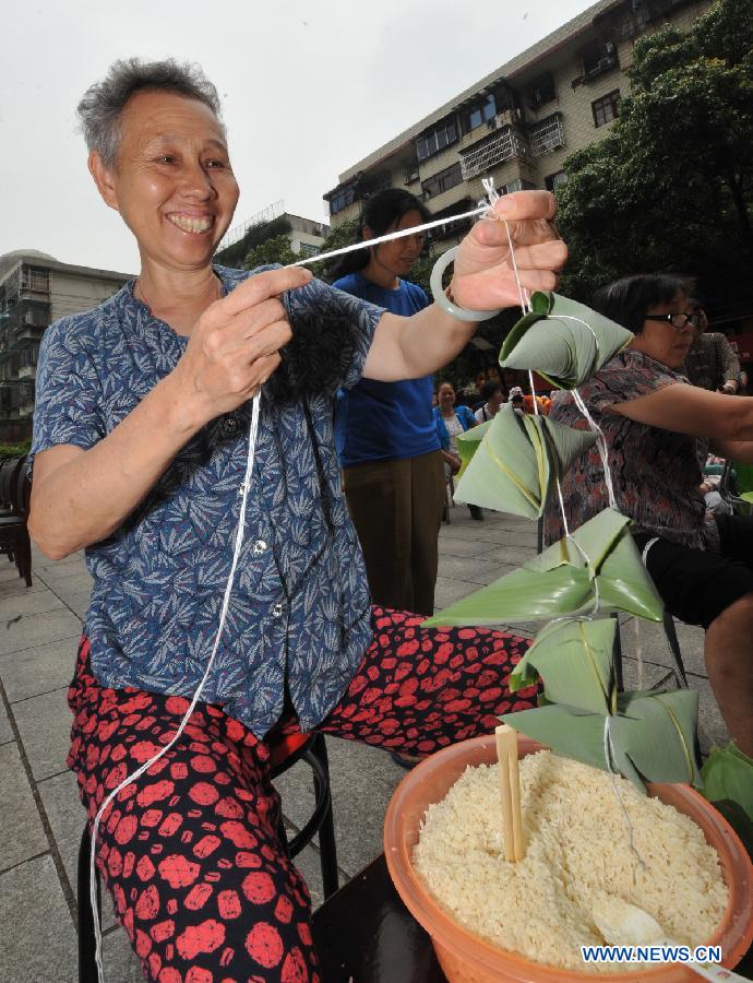 A contestant makes Zongzi, a pyramid-shaped dumpling made of glutinous rice wrapped in bamboo or reed leaves, during a contest in celebration of the upcoming Dragon Boat Festival in Changsha, capital of central China's Hunan Province, June 9, 2013. The Dragon Boat Festival falls on the fifth day on the fifth month on the lunar calendar. (Xinhua/Long Hongtao)