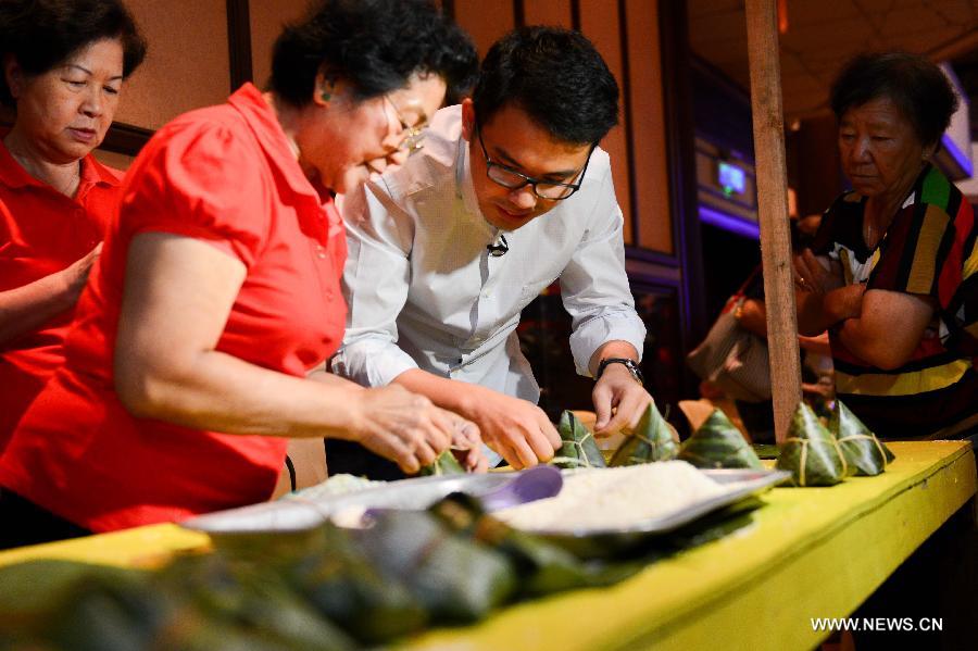 A woman teaches the techniques of making Zongzi, a pyramid-shaped dumpling made of glutinous rice wrapped in bamboo or reed leaves, during a contest in celebration of the upcoming Dragon Boat Festival in Kuala Lumpur, Malaysia, June 9, 2013. The contest was held by a local Chinese association to promote the traditional Chinese festival -- Dragon Boat Festival, which falls on the fifth day on the fifth month on the lunar calendar. (Xinhua/Chong Voon Chung) 