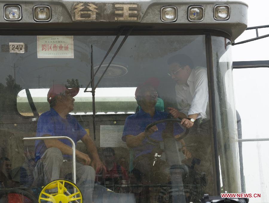 Chinese Premier Li Keqiang (R), also a member of the Standing Committee of the Political Bureau of the Communist Party of China Central Committee, asks about wheat harvest to wokers on a reaper in Peibao East Village of Handan County, north China's Hebei Province, June 7, 2013. Li paid an inspection tour to Hebei Province from June 7 to 8. (Xinhua/Huang Jingwen)