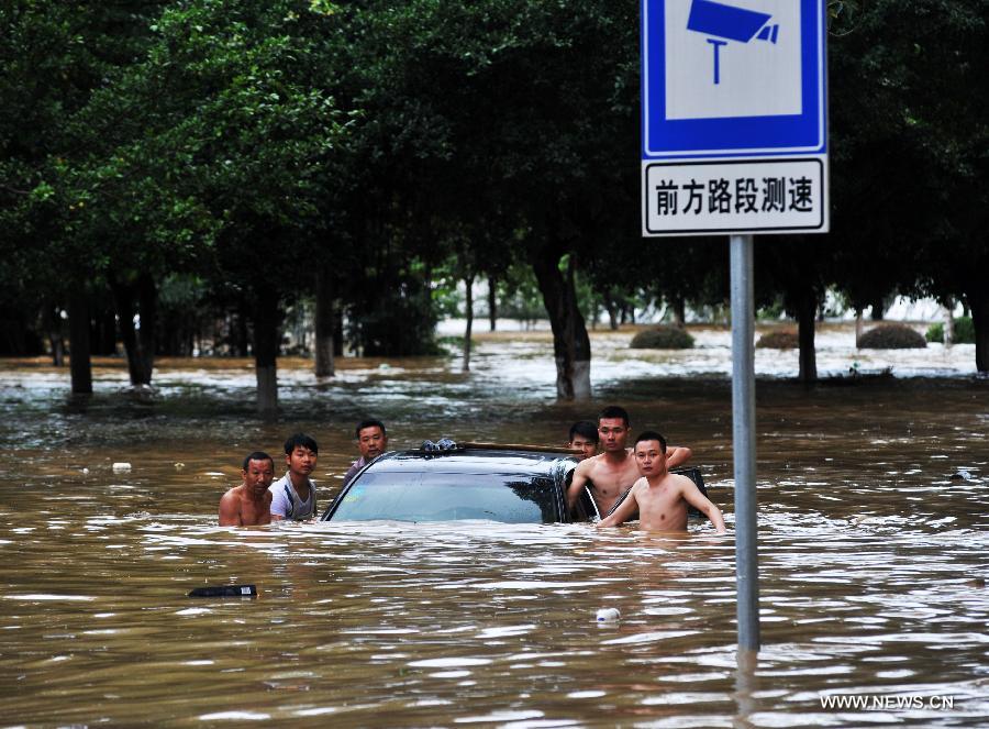Citizens help to remove a trapped car on a flooded road in Liuzhou City, south China's Guangxi Zhuang Autonomous Region, June 10, 2013. Lingering heavy rainfalls in recent days has caused the Liujiang River's water level to rise to 82.7 meters in urban Liuzhou by 11 a.m. Beijing Time (0300 GMT) on Monday, 0.2 meters higher than the warning level. (Xinhua/Li Bin) 