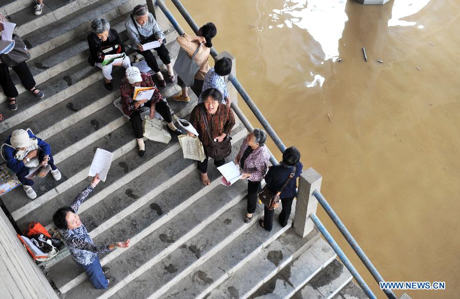 Senior citizens practise singing by the side of a flooded street in Liuzhou City, south China's Guangxi Zhuang Autonomous Region, June 11, 2013. Liujiang River's water level surpassed the warning line in urban Liuzhou on Monday, and started to descend in the night after the flood peak. (Xinhua/Li Bin) 