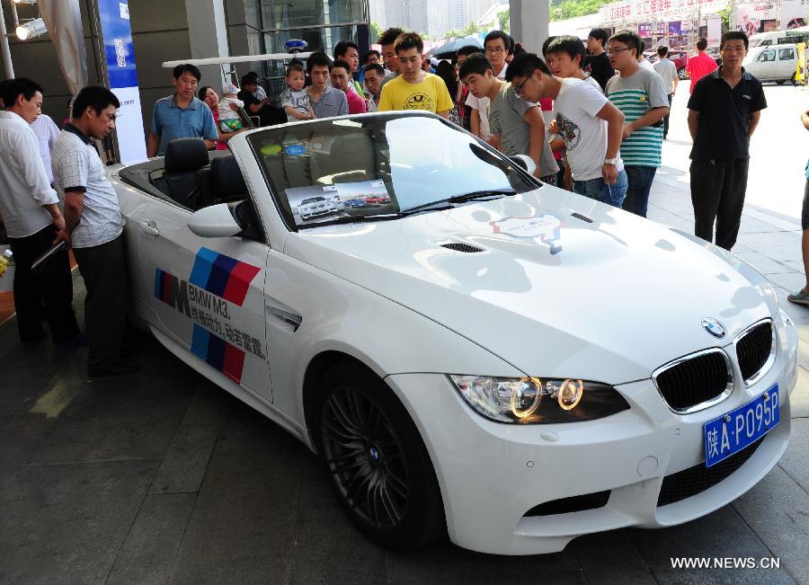 People look at a car displayed at 2013 Xi'an International Automobile Industry Exposition in Xi'an, capital of northwest China's Shaanxi Province, June 12, 2013. Visiting the auto show, which lasts from June 8 to 17, is the way many local residents spent their three-day Dragon Boat Festival vacation from June 10 to 12. (Xinhua/Ding Haitao)