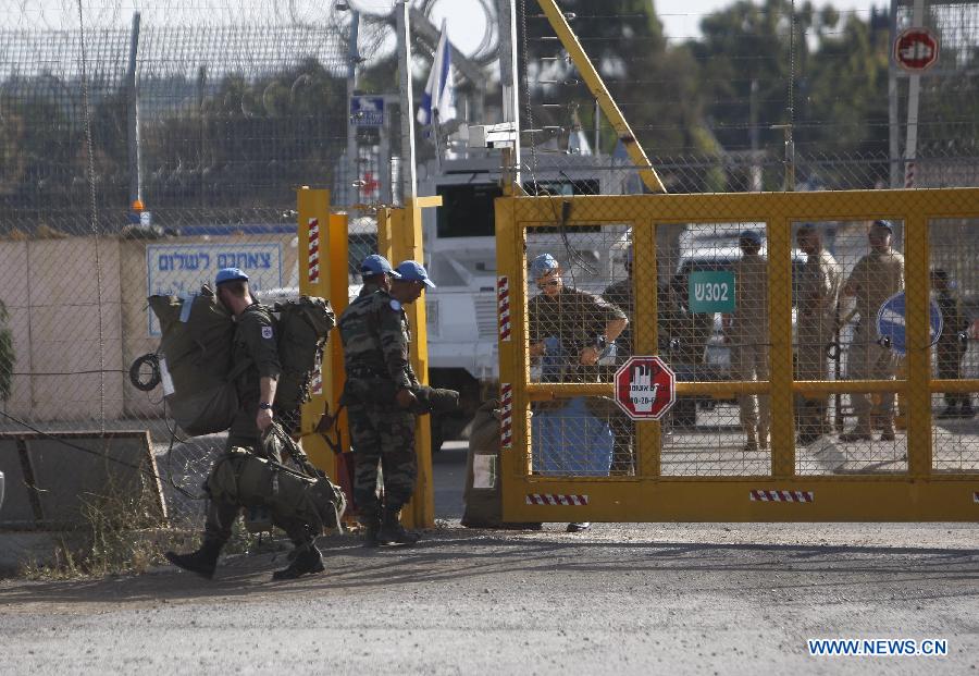 A United Nations peacekeeping soldier from Austria carries his belongings as he enters the Israeli side of the Quneitra border crossing between Israel and Syria, in the Israeli-occupied Golan Heights, on June 12, 2013. Austria has begun withdrawing peacekeepers from the Golan Heights, winding down a four-decade mission due to spillover fighting from the Syrian civil war.(Xinhua/Muammar Awad)