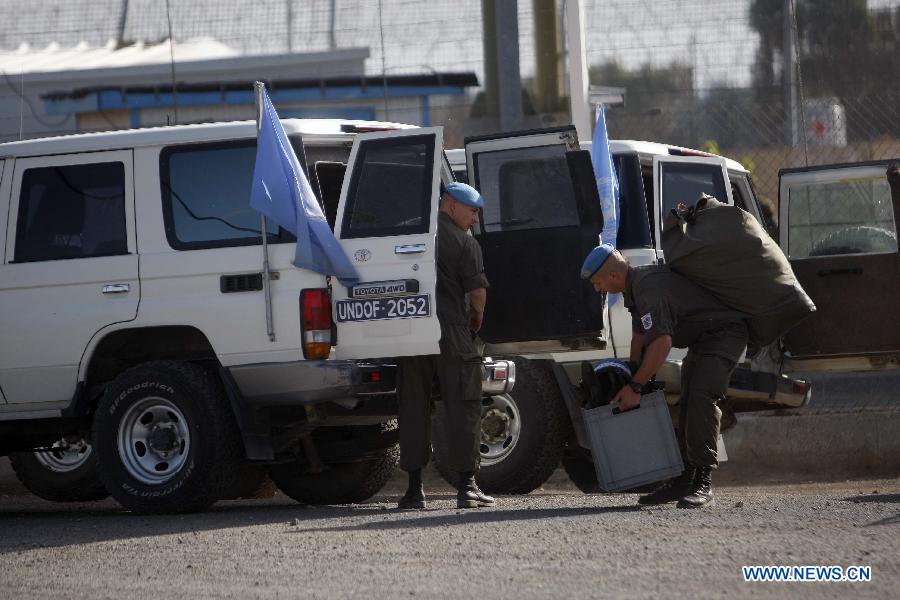 A United Nations peacekeeping soldier from Austria carries his belongings as he enters the Israeli side of the Quneitra border crossing between Israel and Syria, in the Israeli-occupied Golan Heights, on June 12, 2013. Austria has begun withdrawing peacekeepers from the Golan Heights, winding down a four-decade mission due to spillover fighting from the Syrian civil war.(Xinhua/Muammar Awad)