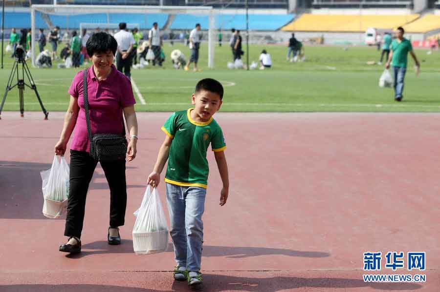 A boy leaves the stadium with a piece of turf he just bought, June 12, 2013. (Photo/Xinhua)