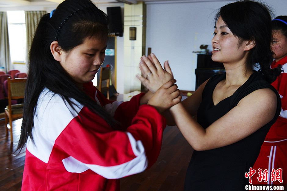 A teacher holds the students' hands and teaches them how to feel the rhythm. (Chinanews/Zhang Yuan)